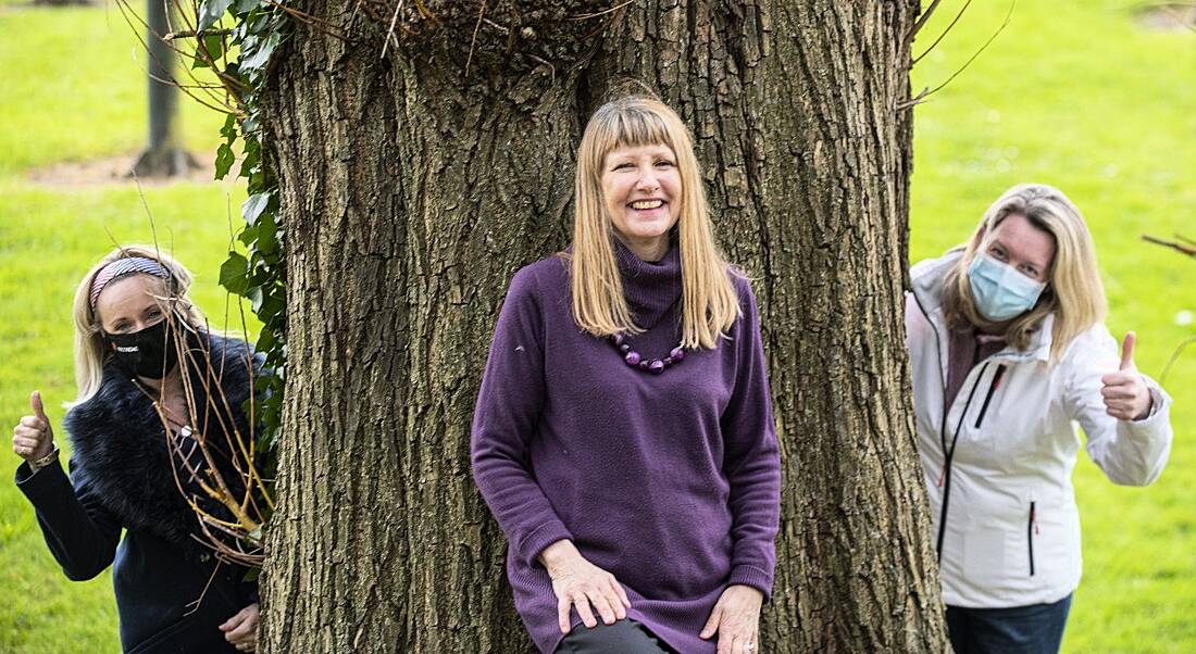 Three women are standing by a tree outdoors, while two are wearing masks and holding up their thumbs for the launch of the Growing Your Potential returnship programme.