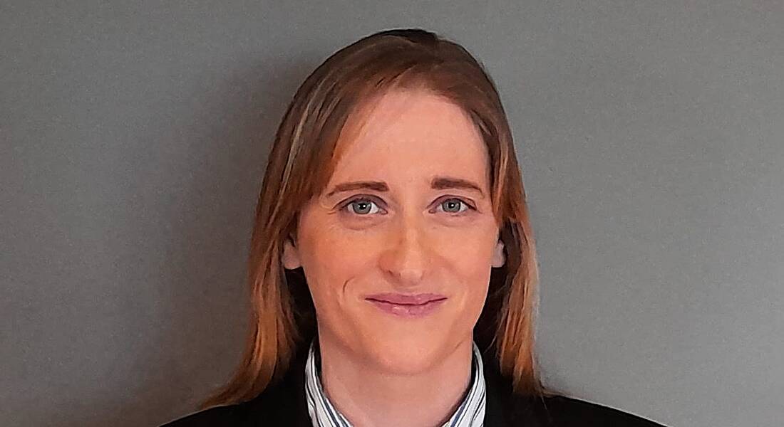 Georgina Molloy, chair of the Women in Engineers Group, is smiling into the camera against a grey background.