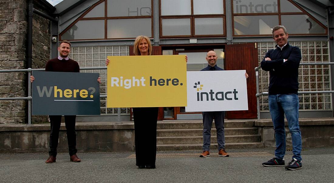 Four team members are standing outside the Intact office in Dundalk, Co Louth, with company signs.