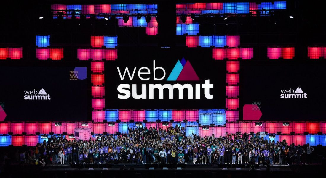 A large crowd of people photographed on a stage decorated with the Web Summit logo and branding.