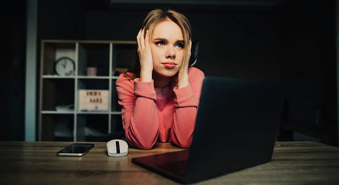 Remote worker sitting at her laptop looking exasperated and tired.