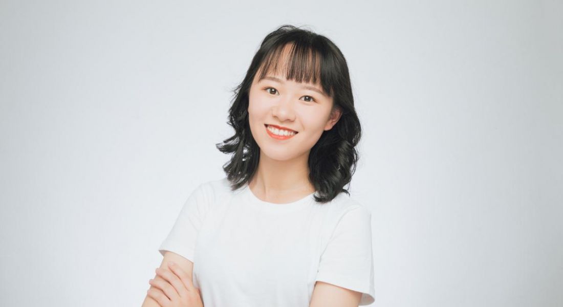 Yujing Huang wearing a white T-shirt, standing with her arms folded.