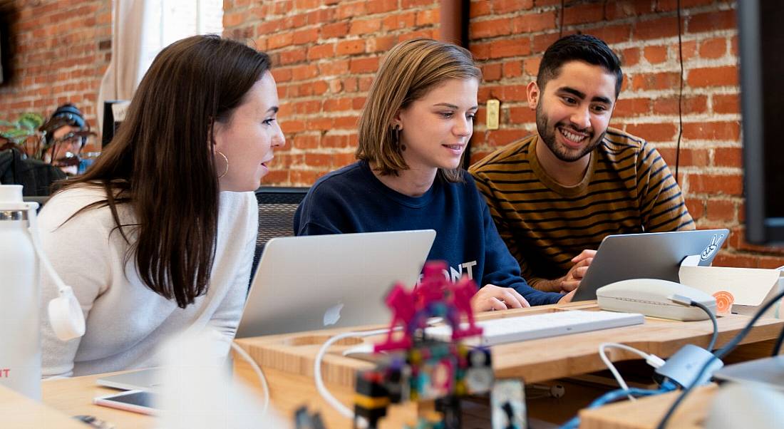 Three employees at CRM company Front at work together in an open-plan office like the one it plans to open in Dublin.