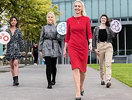 Members of the Four Day Week Ireland campaign standing outside in a formation watching one of their number holding a sign with their logo on it.