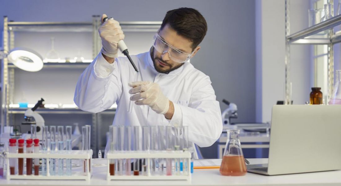 Pharma worker working busily in a lab testing medicines surrounded by lab equipment.