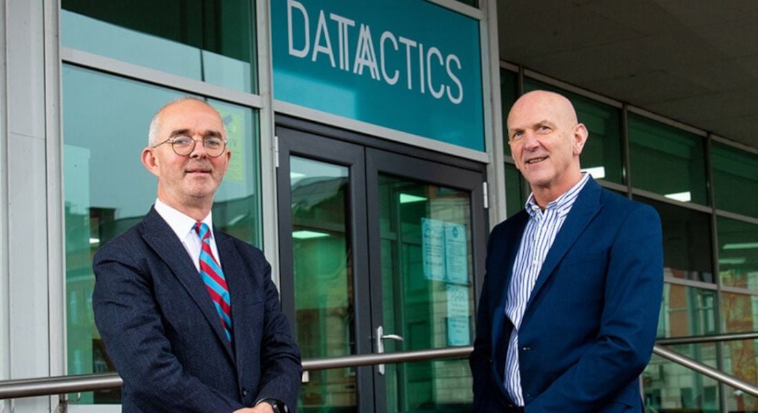 Stuart Harvey, CEO of Datactics, and George McKinney, director of technology and services at Invest NI, posing for a photo in front of the Datactics office in Belfast. Datactics logo on the entrance.