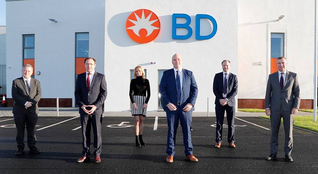 Six members of the BD team standing in front of a white BD building with company logo on the front.