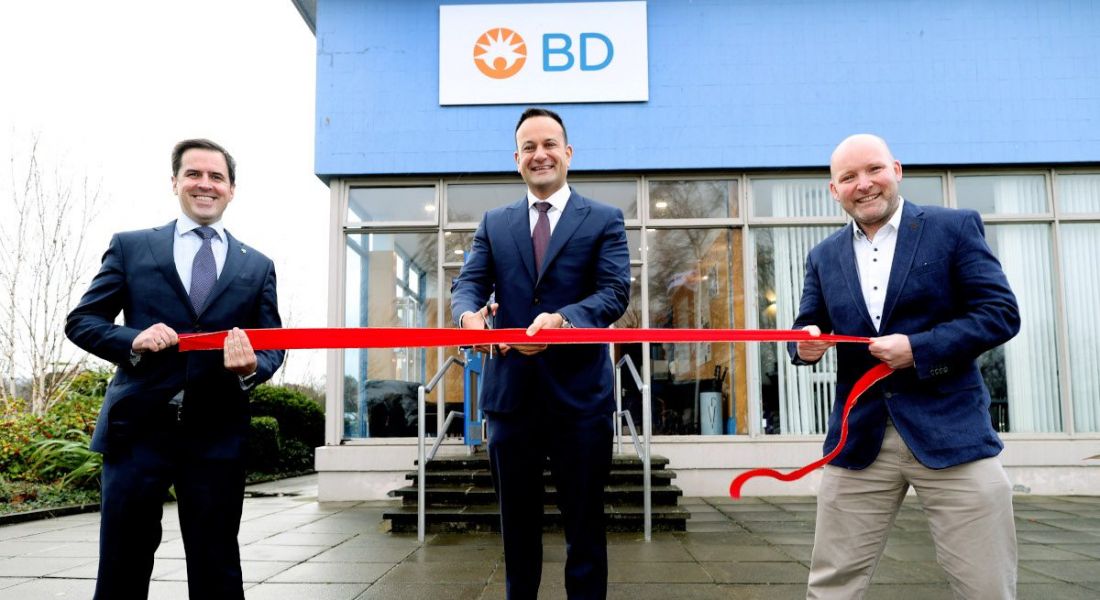 Three men are cutting a ribbon to mark the opening of a BD facility.