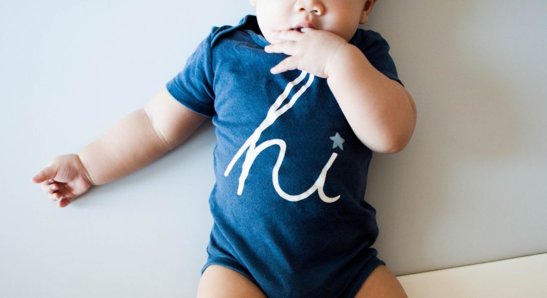 A baby boy is wearing a blue shirt with word 'hi' on it