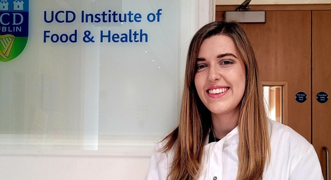 Roisin O'Sullivan, UCD PhD student, pictured wearing a white lab coat outside UCD's institute of food and health.