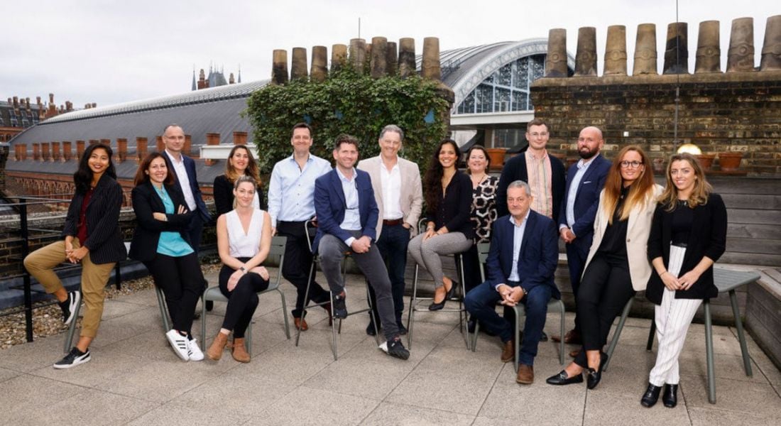 The AccountsIQ team standing and seated in row with chimneys in the background.