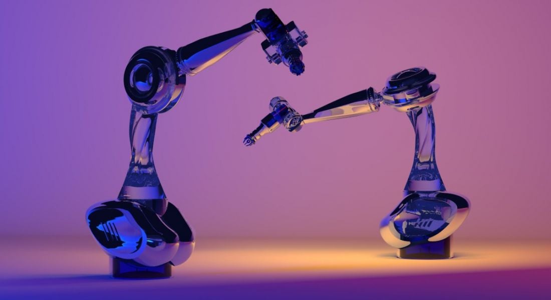 Two robotic arms in automation concept illuminated by purple light.
