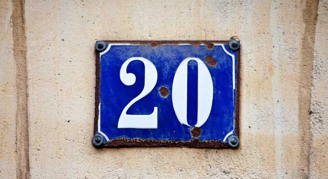 The number 20 in white letters on a blue plaque nailed to a beige wall.