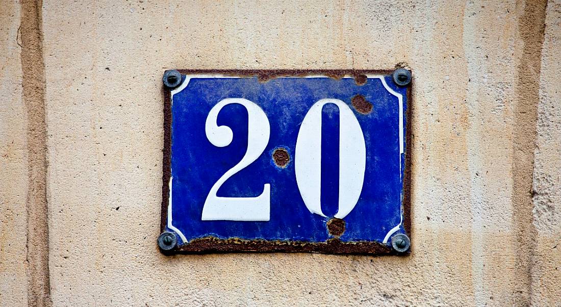 The number 20 in white letters on a blue plaque nailed to a beige wall.