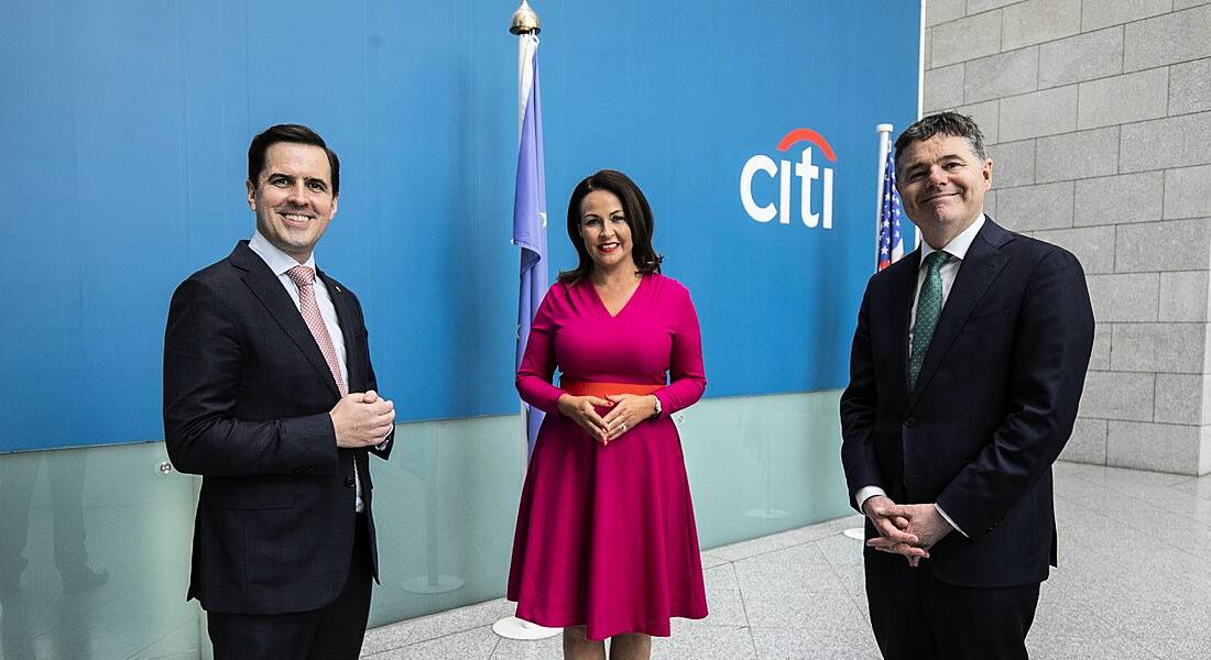 Martin Shanahan, Cecilia Ronan and Paschal Donohoe stand in an office space in front of a wall with the Citi logo on it.