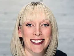 Orla Moran of IrishJobs.ie standing against a feature wall with vertical orange lines.