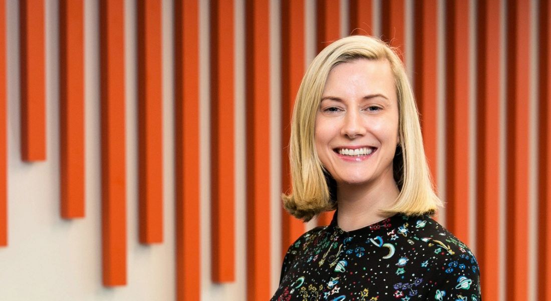 Orla Moran of IrishJobs.ie standing against a feature wall with vertical orange lines.