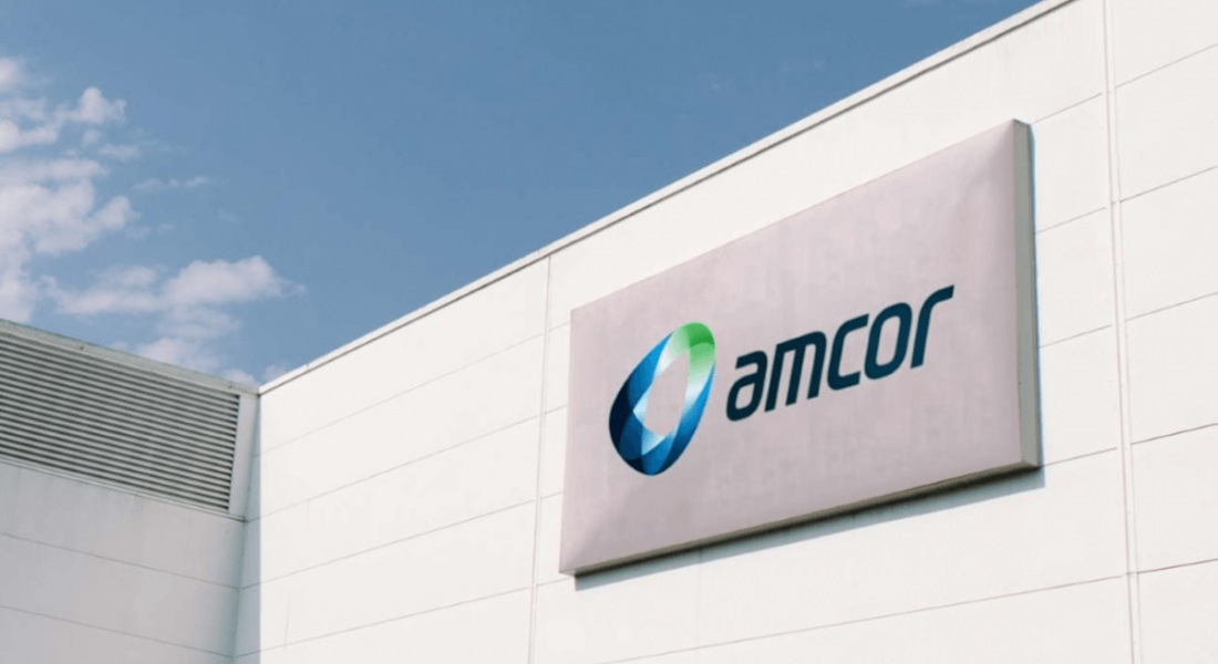 The Amcor logo on the side of a building underneath a blue sky.