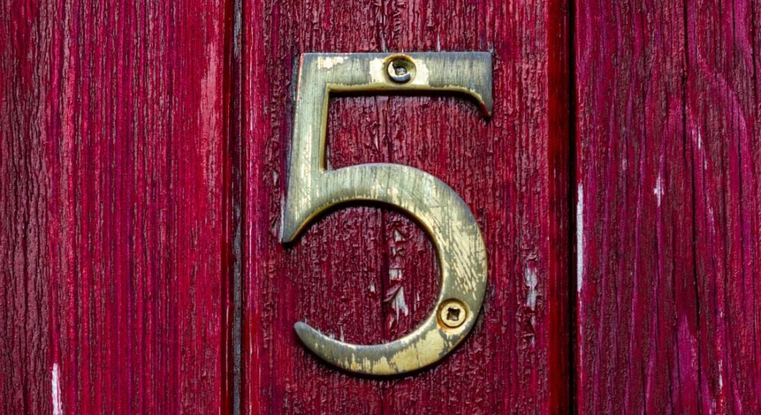 A gold number five on a dark red wooden door to represent the five people management skills in the article.