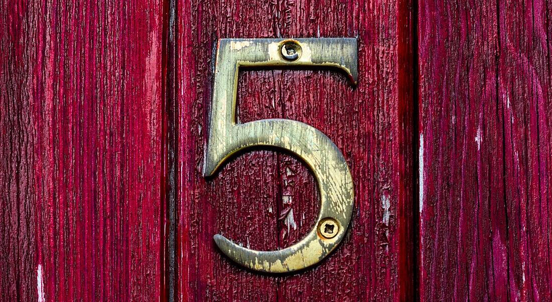 A gold number five on a dark red wooden door to represent the five people management skills in the article.