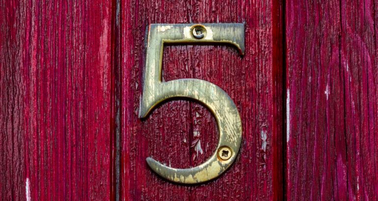 A gold number five on a dark red wooden door to represent the five people management skills in the article.
