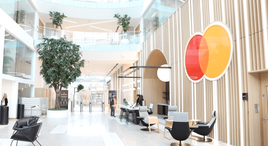 A bright, spacious office lobby with the Mastercard symbol on the wall.