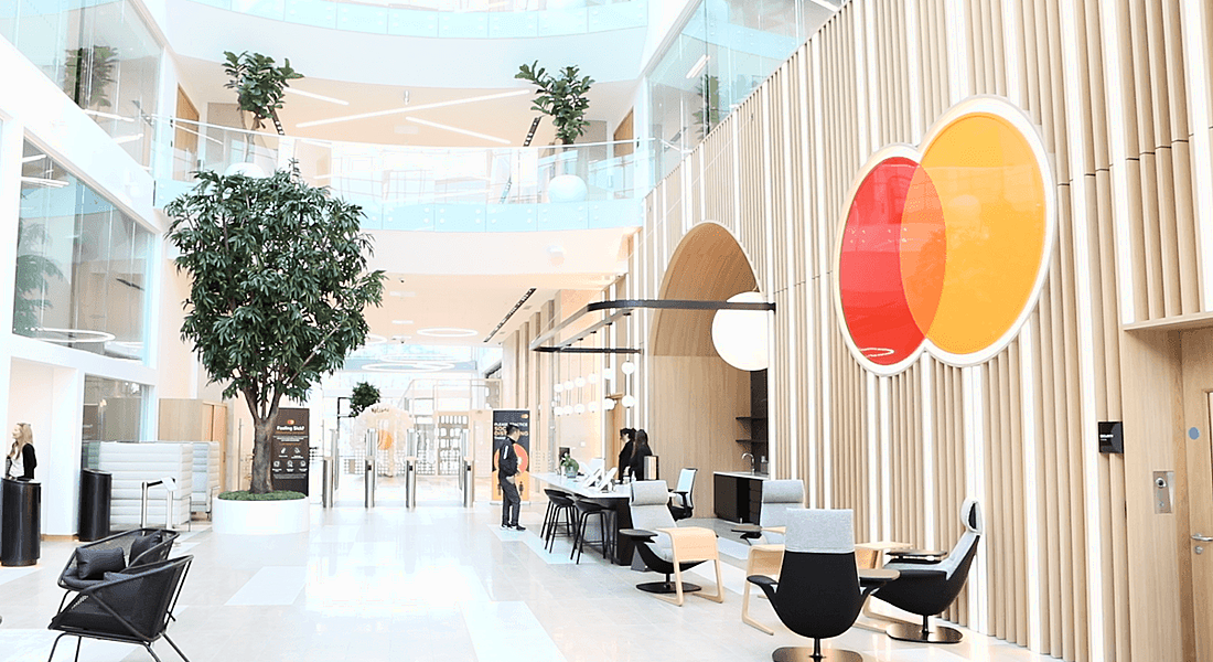 A bright, spacious office lobby with the Mastercard symbol on the wall.