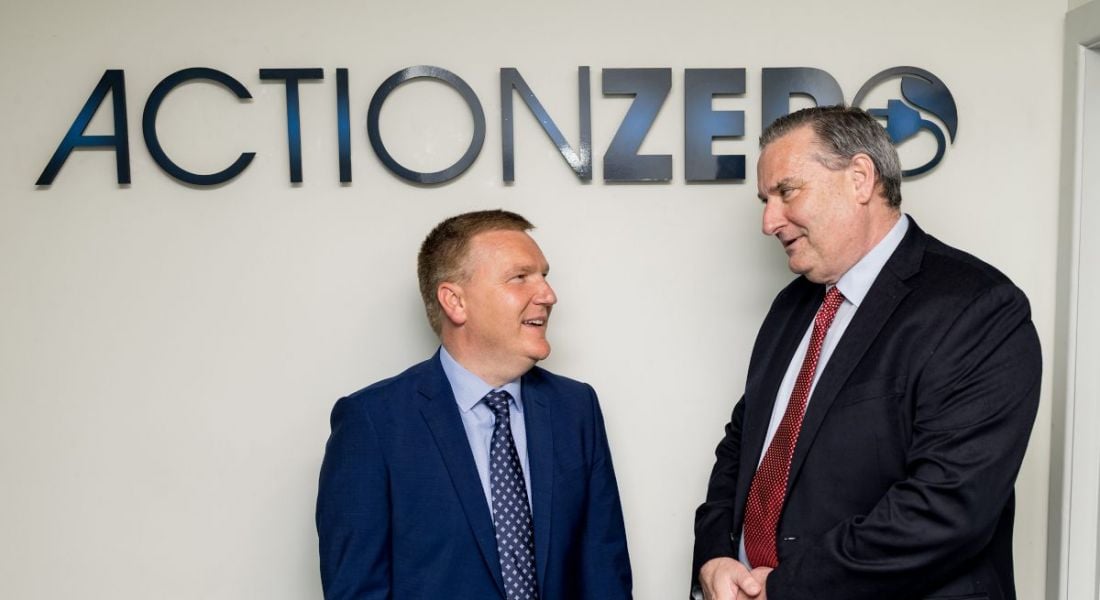 Minister for Public Expenditure and Reform Michael McGrath, TD, and ActionZero CEO Denis Collins with the ActionZero logo on a wall behind them.