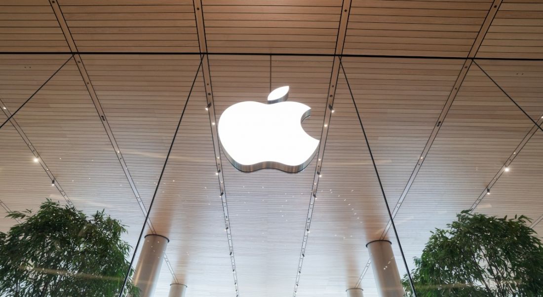 Apple logo on a glass storefront with two trees either side.