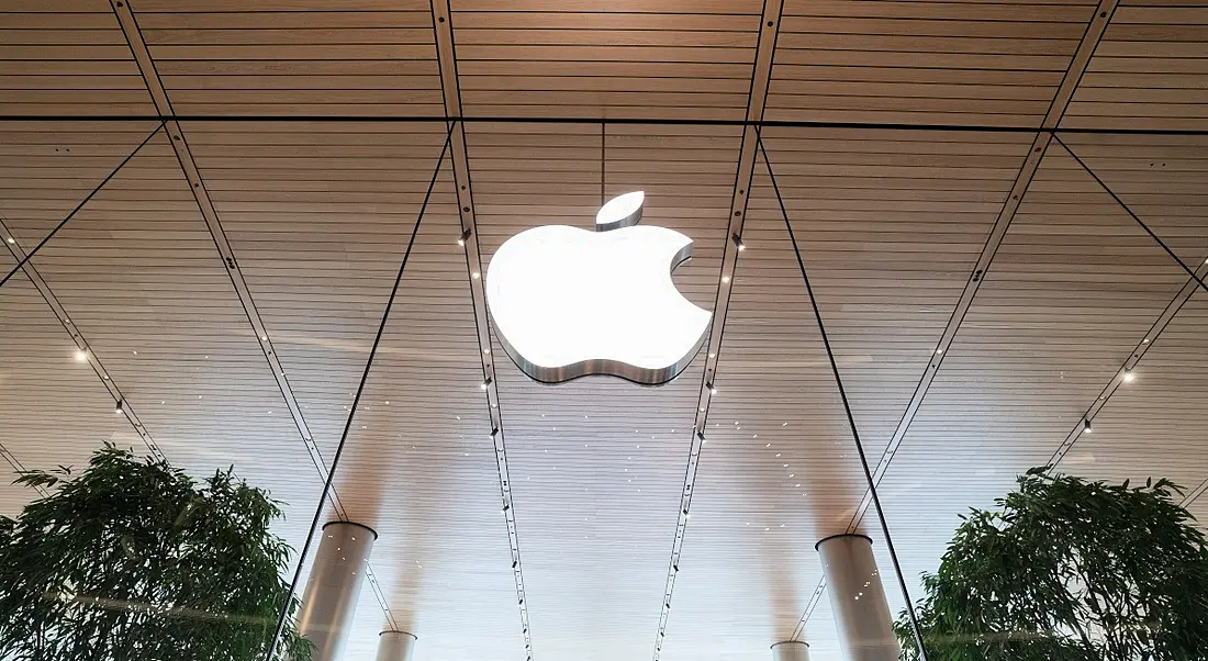 Apple logo on a glass storefront with two trees either side.