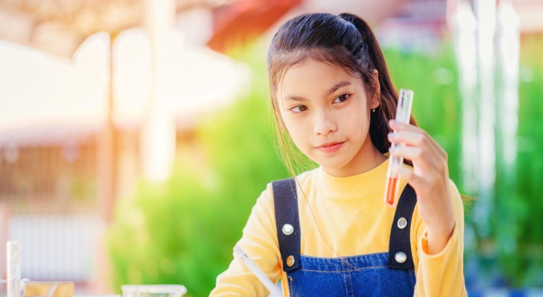 Teenage girl holding a pipette as if she is doing a science experiment.