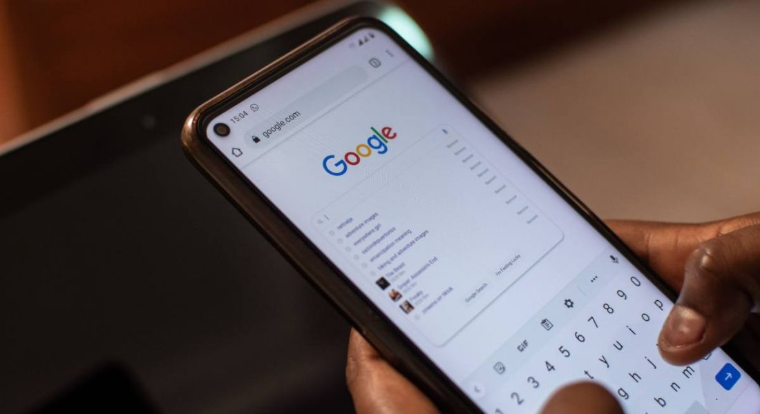 Person holding a smartphone using Google and typing something into the search bar.