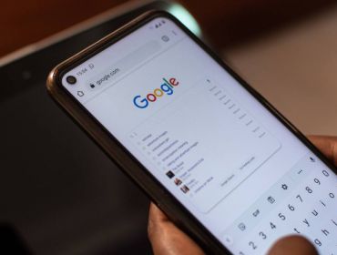 Person holding a smartphone using Google and typing something into the search bar.