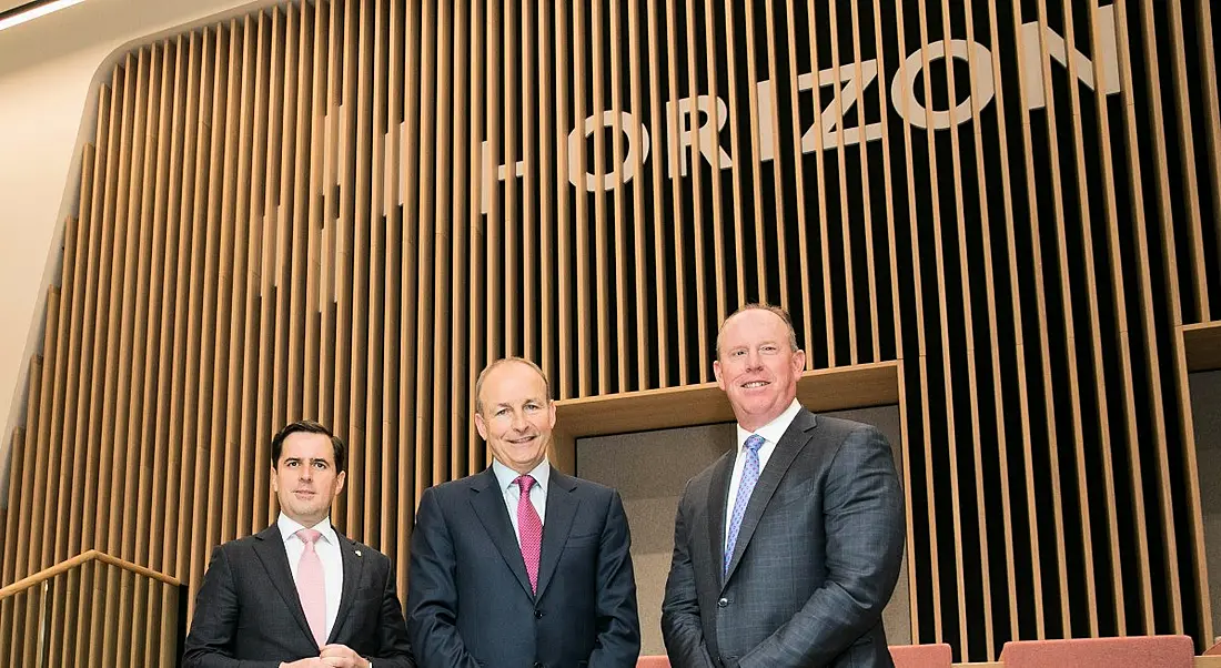 Three men standing in a room with wood-panelled walls and the Horizon logo.