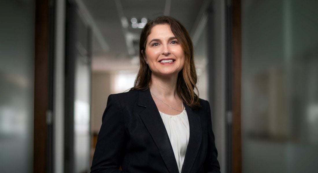 Portrait of Rachael Ingle, CEO of Aon Ireland, standing against some glass doors.