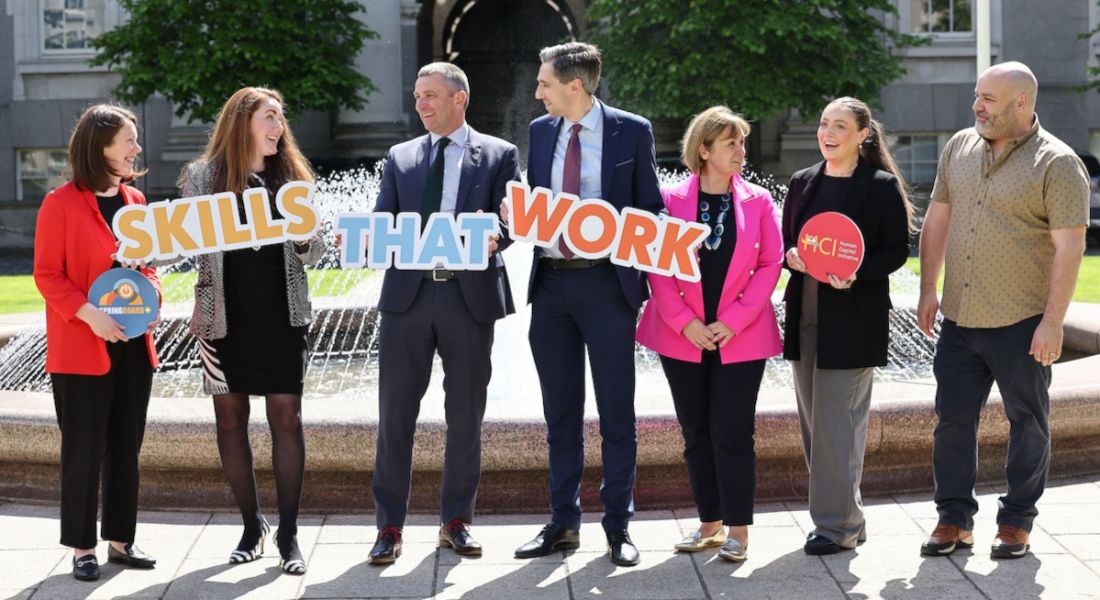 Seven people standing in a row holding signs that read 'skills that work' to celebrate the launch of Springboard+ 2022.