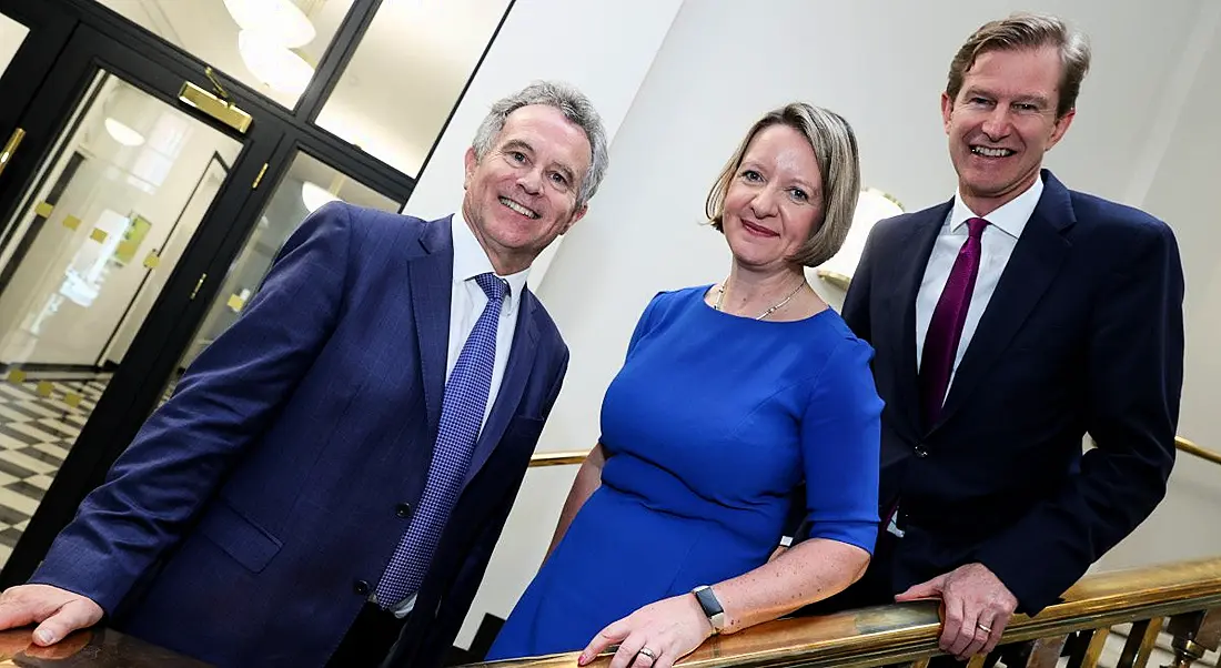 OFX leaders Maeve McMahon and Skander Malcolm standing on a staircase next to Seán Fleming, TD.