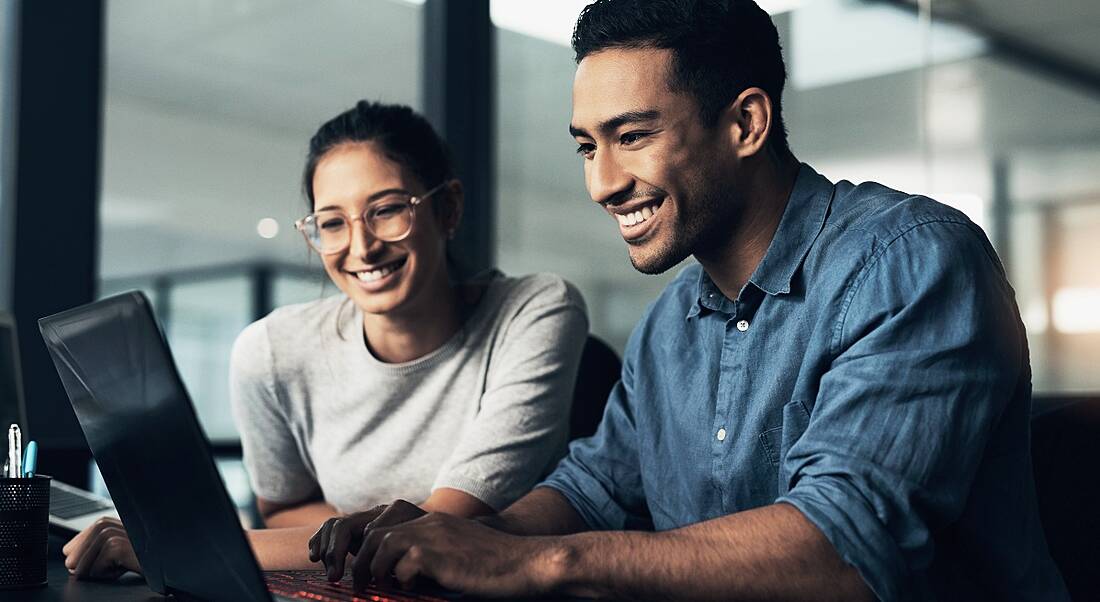 Two young people work at a laptop.