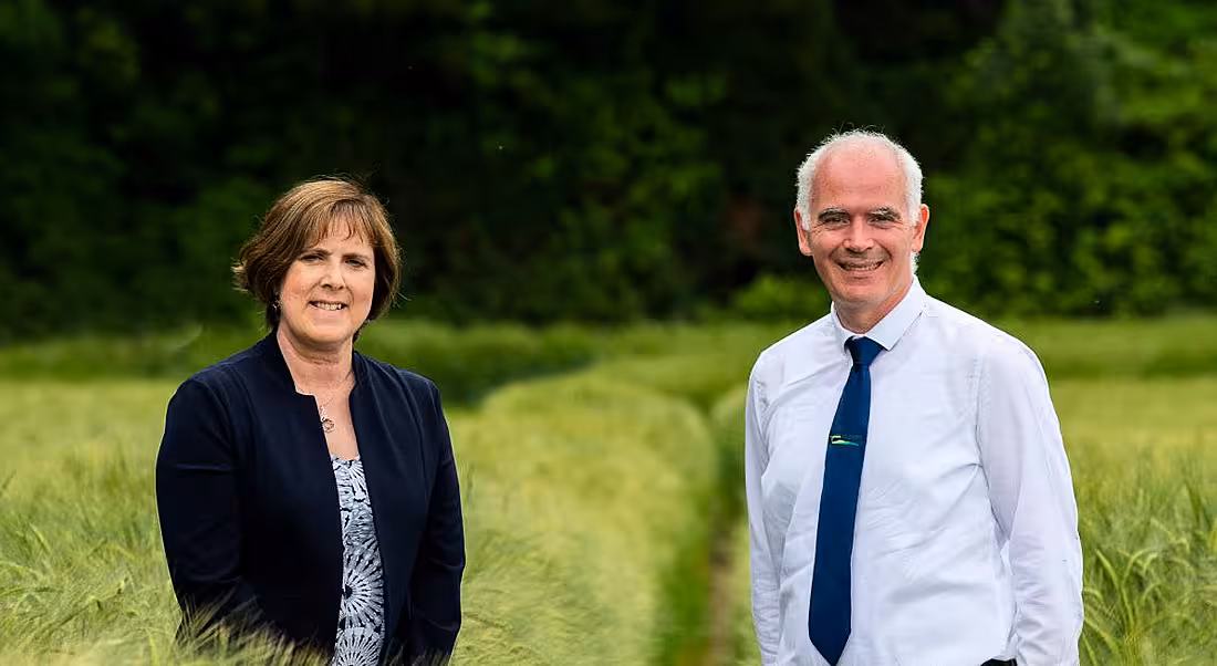 A woman and a man standing in a green field.