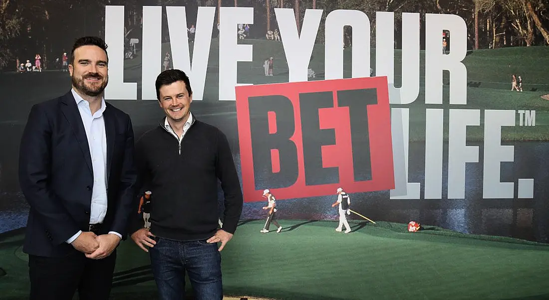 Two men standing together in front of a wall that says "Live your bet life". They are Johnny Aitken and Mark Hughes of PointsBet.