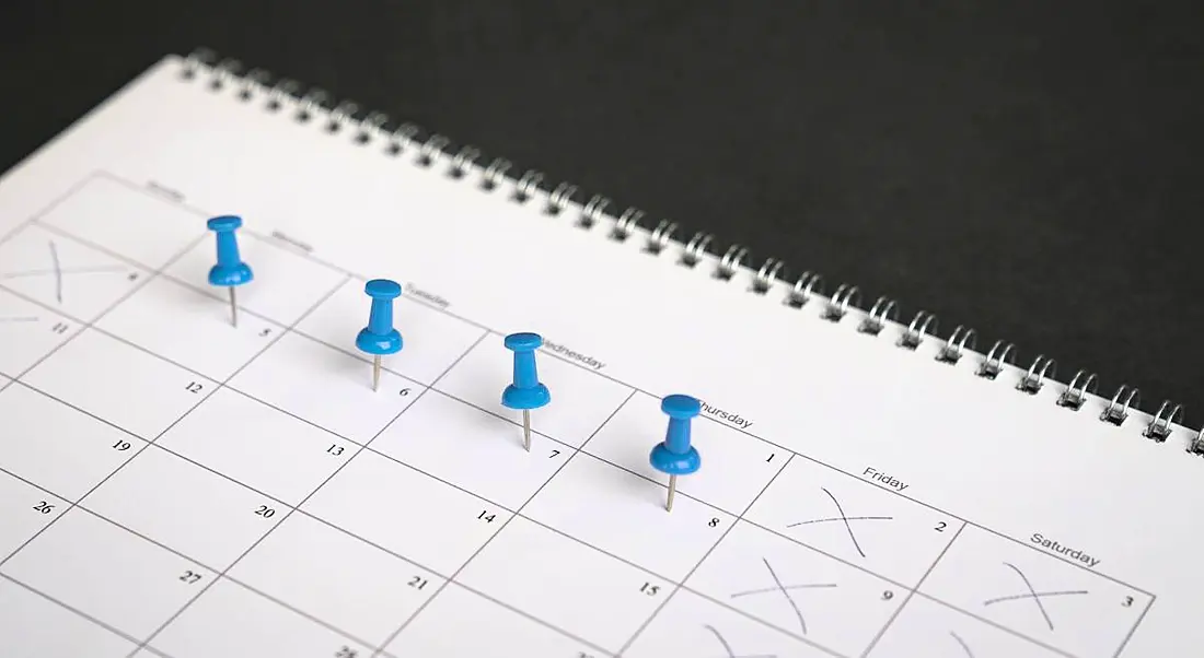 A close-up of a calendar with four blue push pins on it, symbolising a four-day week.