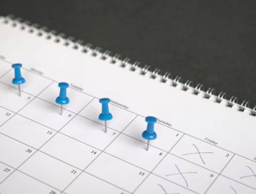 A close-up of a calendar with four blue push pins on it, symbolising a four-day week.