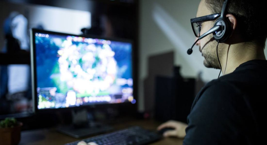 A young man wearing a headset sitting at a laptop playing a game to boost employee engagement.