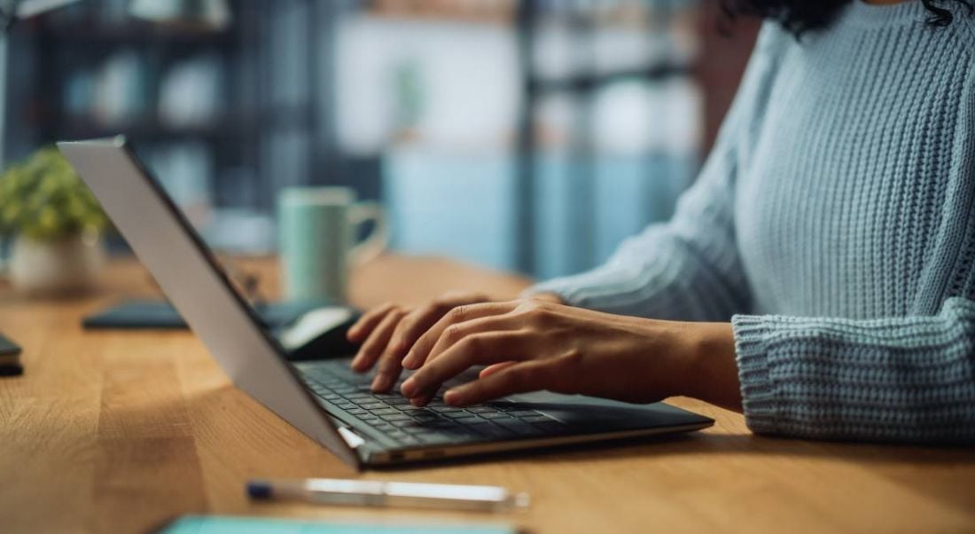 A close-up of a woman’s hands typing on a laptop, working on her tech CV.