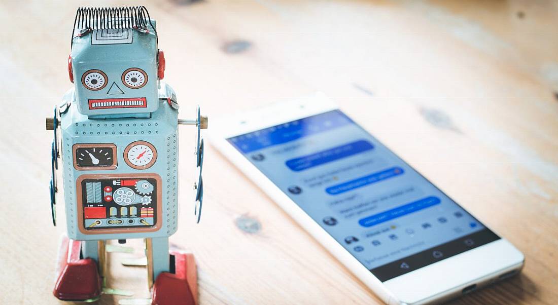 A small blue toy robot stands on a wooden surface.