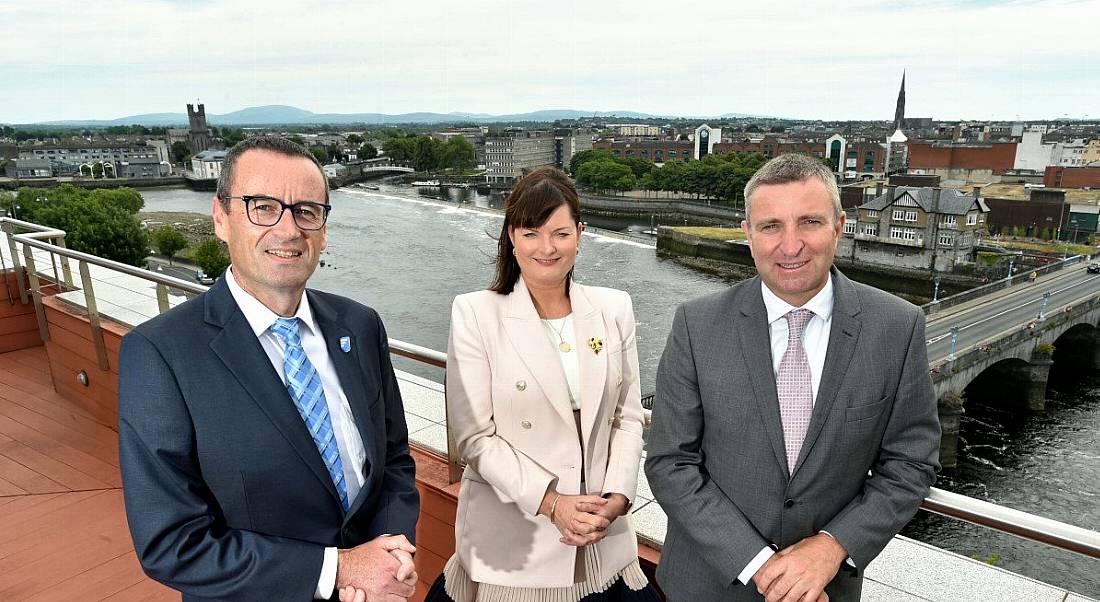 Two men and a woman in the centre standing on a balcony overlooking a city following the announcement of 50 new jobs at FileCloud.