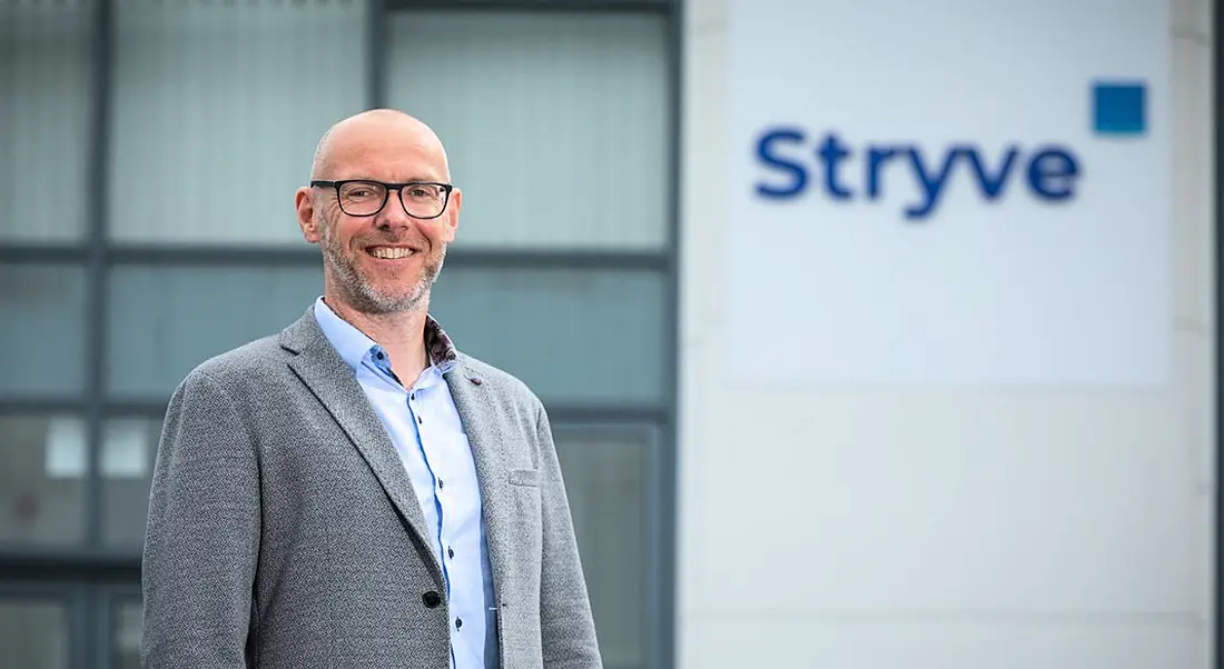 Stryve CEO Andrew Tobin standing outside a building with the Stryve logo on it in blue letters.