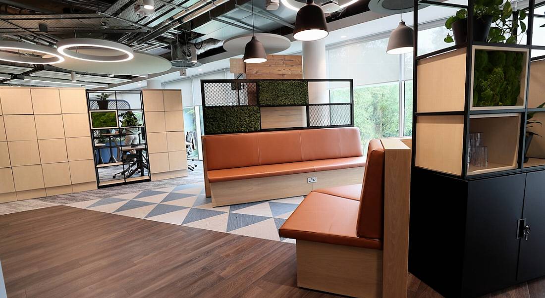 A brightly lit communal space in the Fidelity Investments office with large couches and greenery around it.