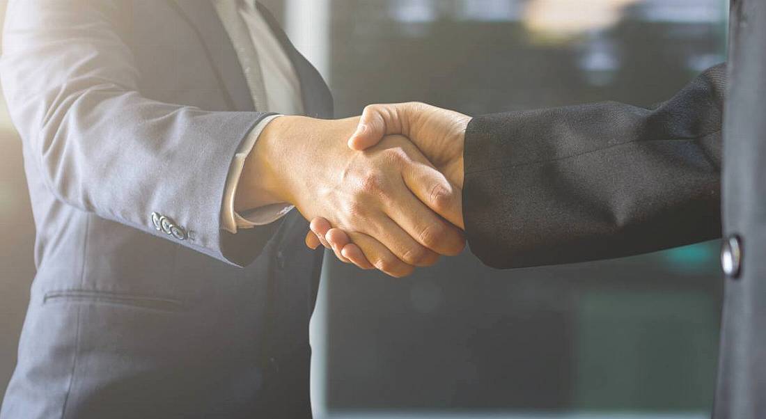 Two people in suits shaking hands.