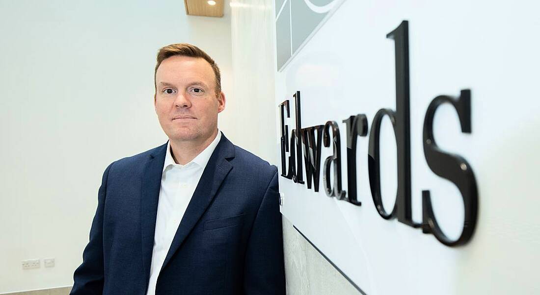 A man in a suit stands alongside a sign that says Edwards Lifesciences.